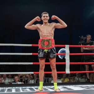 Un élève sur un ring de boxe, souriant et célébrant sa victoire après un combat.